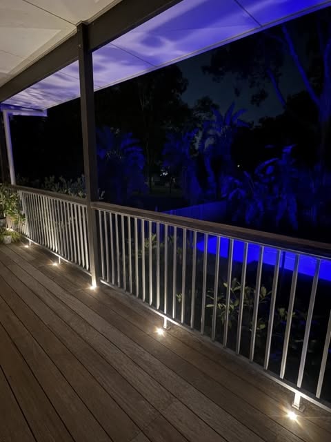 Timber deck with warm low-level lighting and blue garden lighting at night